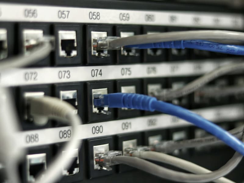 Patch panel com cabos de rede azuis conectados e portas numeradas