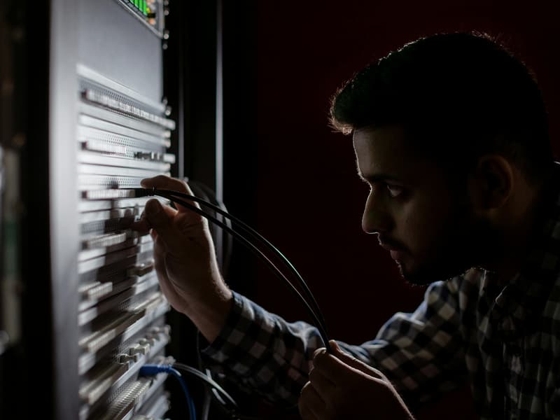 Profissional de TI conectando cabos em um rack de equipamentos